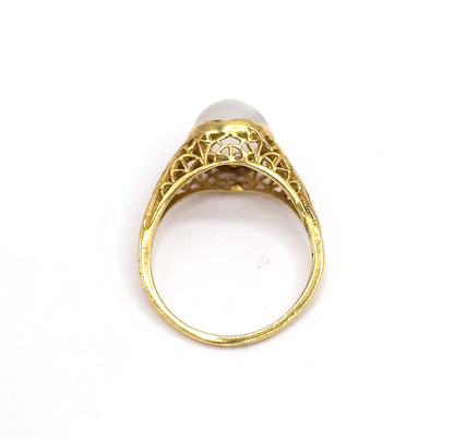 Upright view from behind against white, looking straight through the open shank to the pierced filigree gallery and the underside of the bezel, with the moonstone just visible beyond.