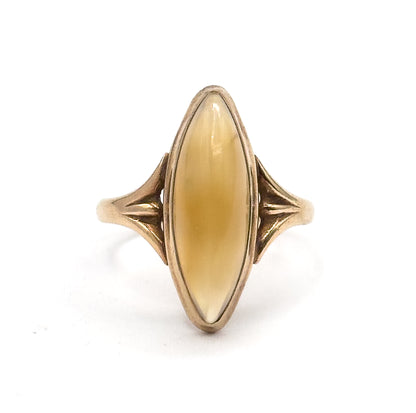 Straight-on view of the face against white, the long navette cabochon glowing honey-gold within its rose gold bezel, with ribbed fan shoulders flaring symmetrically on both sides.