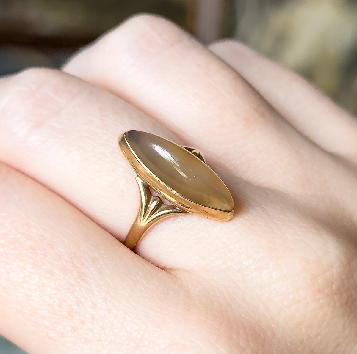 Angled view from above the hand, the honeyed marquise cabochon filling the rose gold bezel while the shank narrows between the fingers.