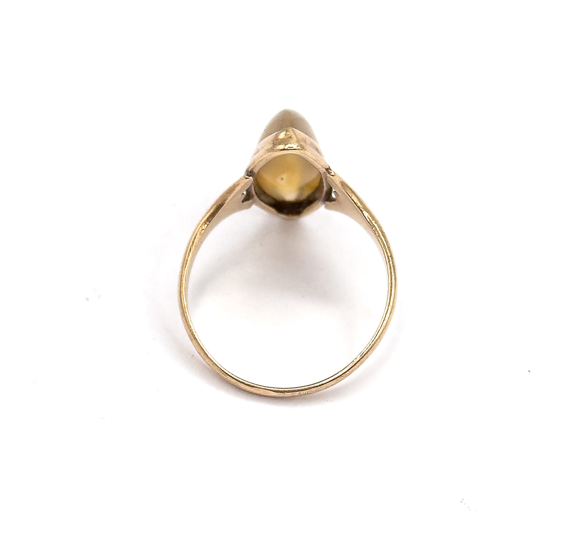 Off the hand and standing upright against white, seen through the open circle of the shank so the underside of the navette bezel and its prongs face the viewer.