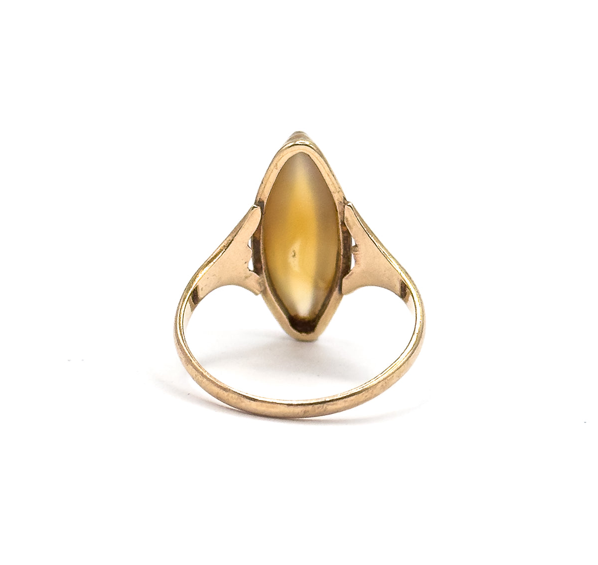 Standing upright against white, the underside of the navette bezel shows the golden brown cabochon from behind with small pierced openings in the gallery at either side above the slender shank.