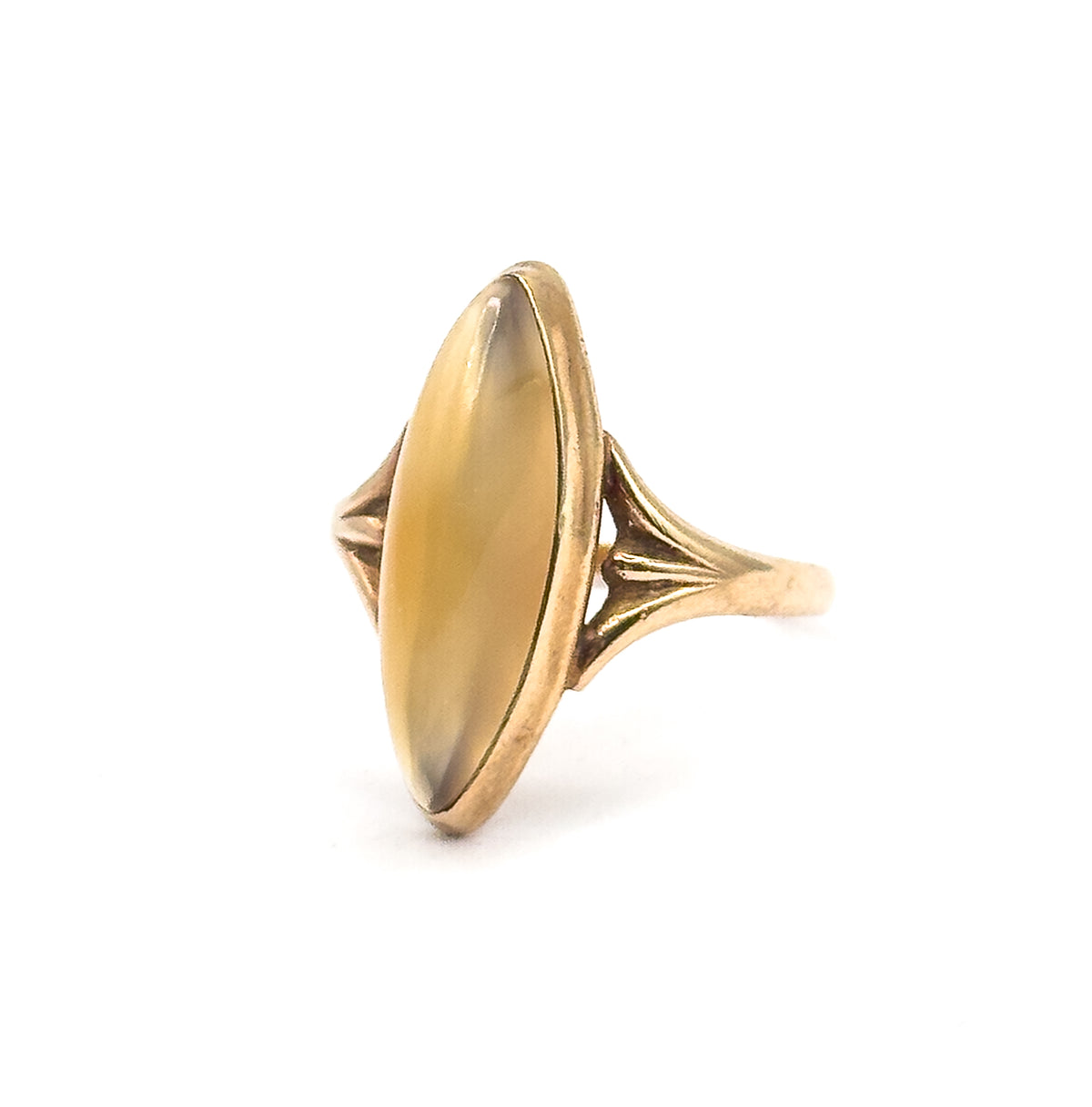 Three-quarter front view against white with the full elongated navette face of the golden brown cabochon on show, the ribbed fan shoulder and slim shank angling back to the right.