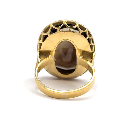 Straight on from the back, a large oval opening in the yellow gold plate frames the underside of the smoky quartz, ringed above by scalloped cut-outs, with the shank looping below.