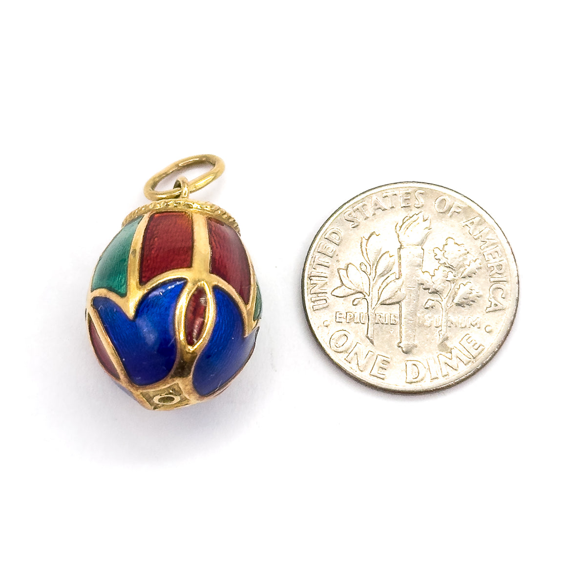 An enamel egg charm in 14K yellow gold, shown upright beside a dime for scale, its blue, red and green panels divided by gold ribs with a rope-textured collar and round bail on top.