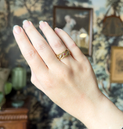 The hand is held up against a soft painted backdrop, the wide two-tone band small on the ring finger, giving a sense of its scale against the whole hand.