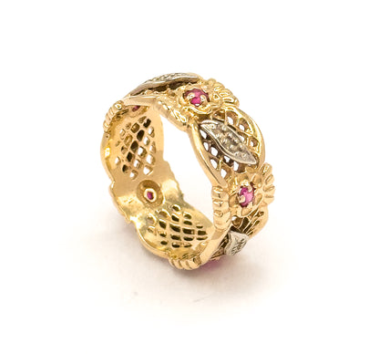 Standing upright off the hand on a plain white surface, showing the full circle of the band with its pierced lattice panels, flower heads and leaf sections around the whole shank.