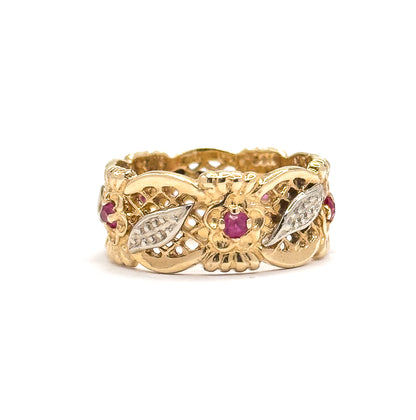 Front view of the band lying flat, centred on the flower motif with its deep pinkish red stone, a pale leaf panel either side and further red stones curving away at the edges.