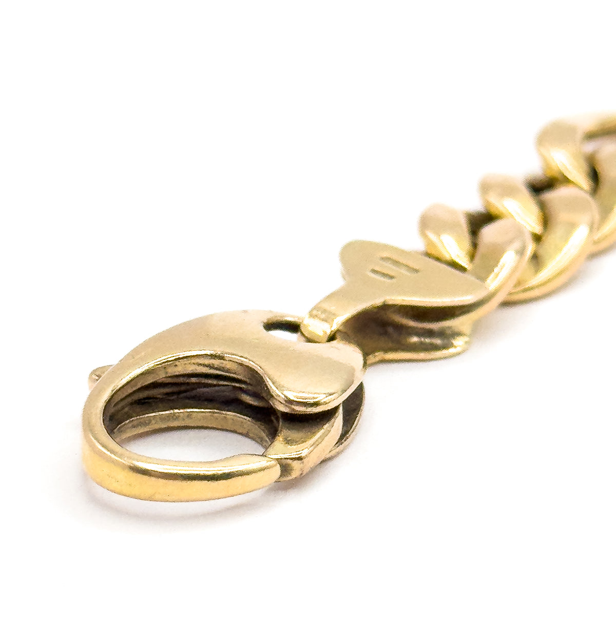 An extreme close-up along the length from the clasp end, the large open loop of the lobster clasp filling the foreground and the yellow gold Figaro links receding away out of focus.