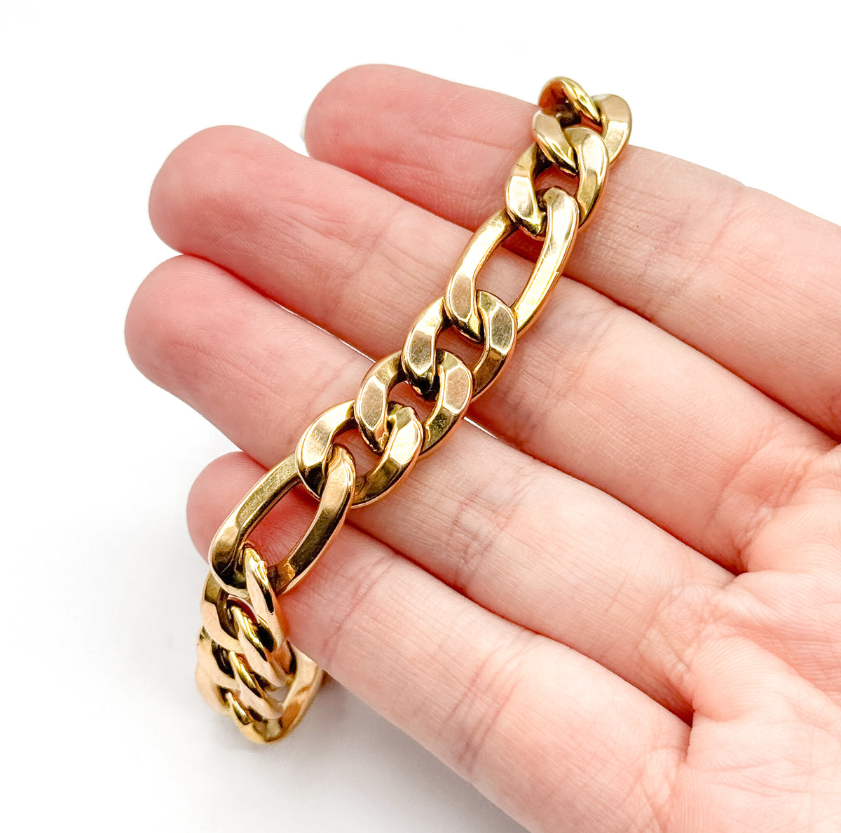 Laid diagonally across four fingers, the chain's width spans nearly a full fingertip, giving a clear sense of how chunky the polished yellow gold links are.