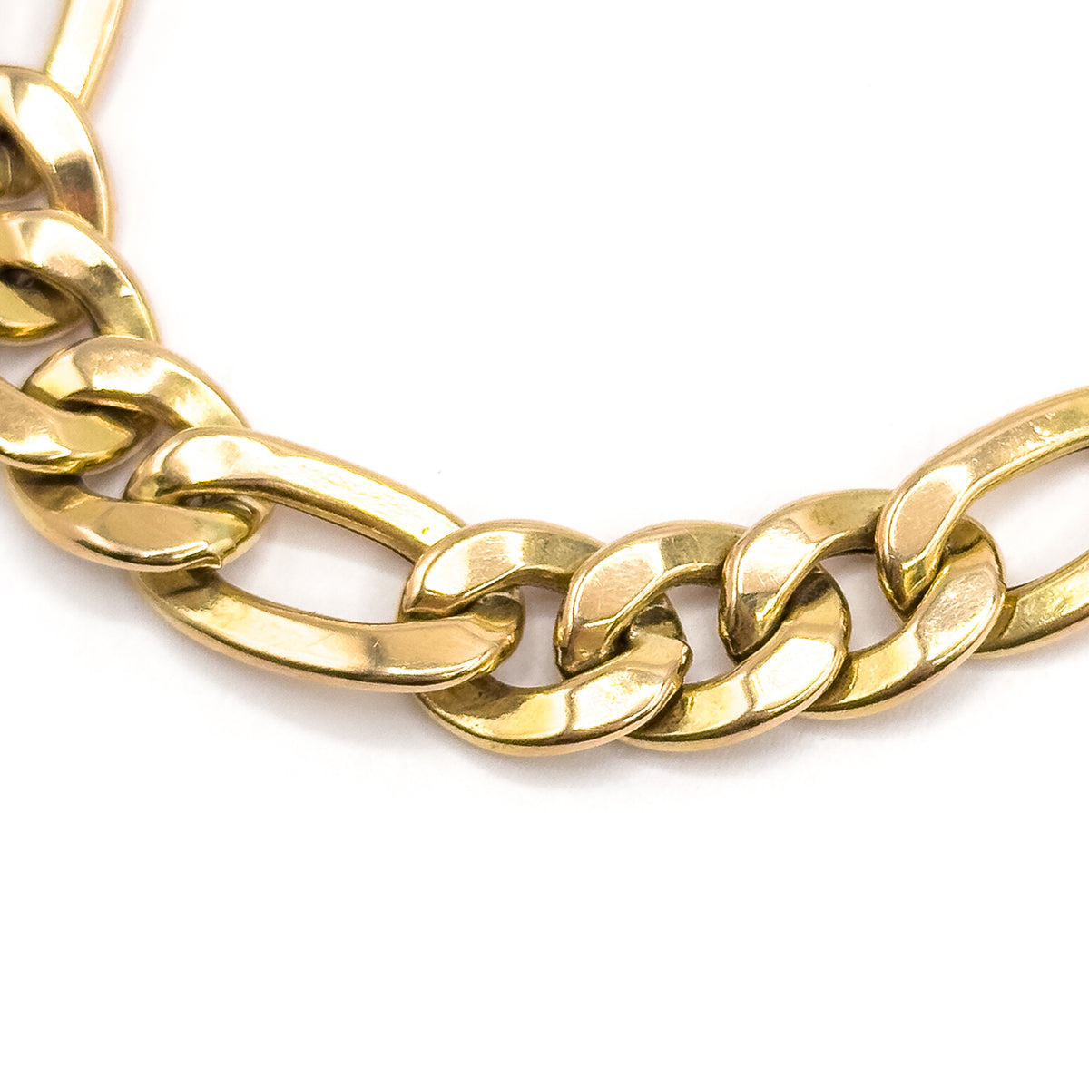 A tight macro of just a few links curving across white, each polished yellow gold loop showing its smooth rounded shoulder and the flat bevel where links meet.