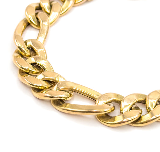 A steeply angled close view with the chain arcing away into the distance, the single elongated link at centre turned broadside to show its long flat polished face in yellow gold.