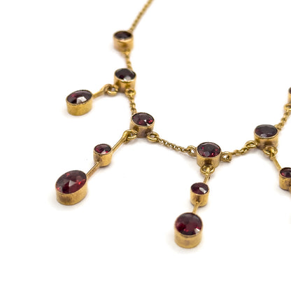 Looking along the necklace from one side, the chain climbing out of frame at the top while the fringe drops step down diagonally, the deep bezel collars seen in profile against plain white.