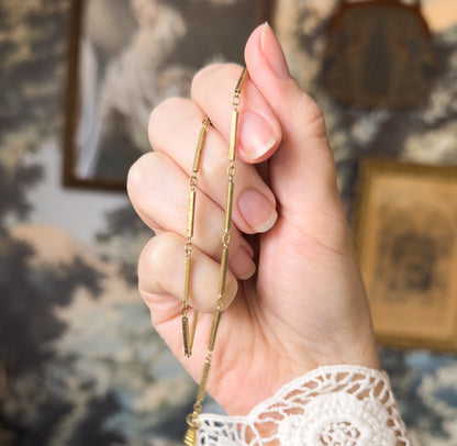 The chain draped over the back of the fingers, a doubled run of narrow bar links joined by small round jump rings descending past the knuckles toward the wrist.