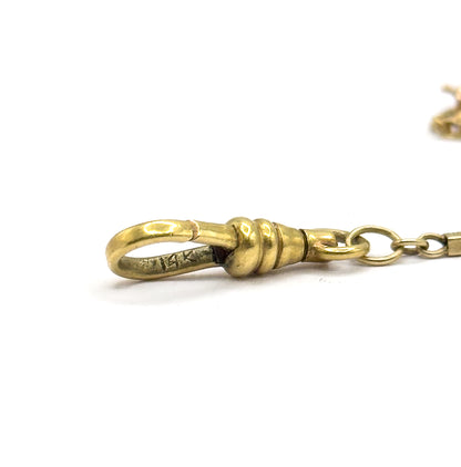 Close macro against white of the dog clip alone, its hooked loop carrying a small stamped mark and its ribbed collar meeting a round jump ring that leads off to the bar links.