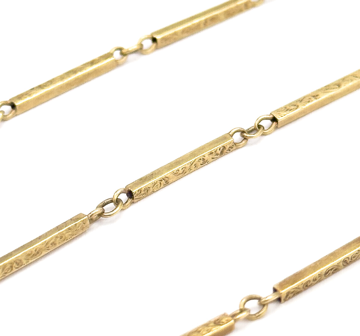 Three diagonal runs of the chain crossing the white field together, letting you compare the scrolled bar faces with the plain flattened ends that the small round jump rings pass through.
