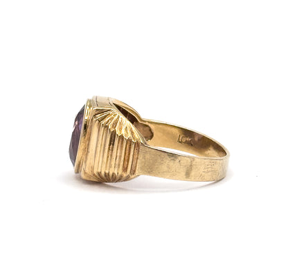 Close side view from the other flank, the fanned rays and vertical fluting of the shoulder filling the frame while a sliver of the purple stone shows at the bezel's edge on the left.