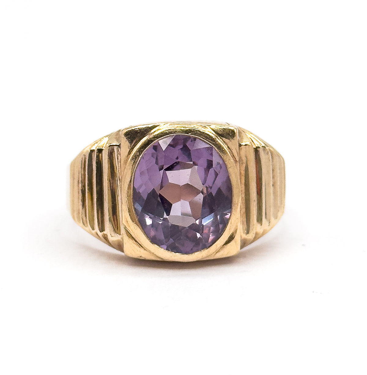 Upright against a plain white background, the ring's face fills the frame so the oval sapphire's lilac facets and the stepped ridges of each shoulder are seen head-on.