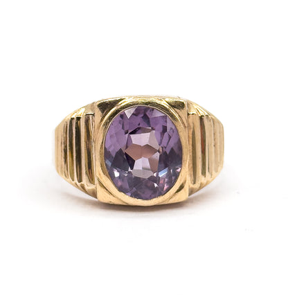 Upright against a plain white background, the ring's face fills the frame so the oval sapphire's lilac facets and the stepped ridges of each shoulder are seen head-on.