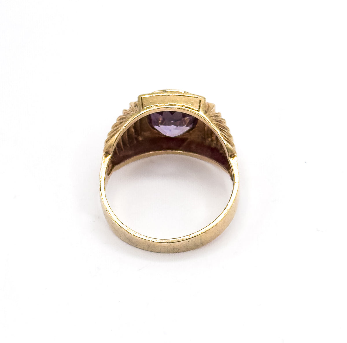 Viewed from behind through the open shank, the underside of the bezel shows the sapphire's pavilion glowing pale violet between the two textured shoulders.