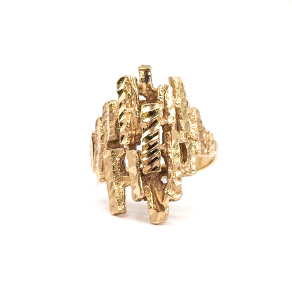 Head-on view of the face against white, the crisscrossing faceted yellow gold bars filling the frame like a lattice, with the shank just visible behind at the right.