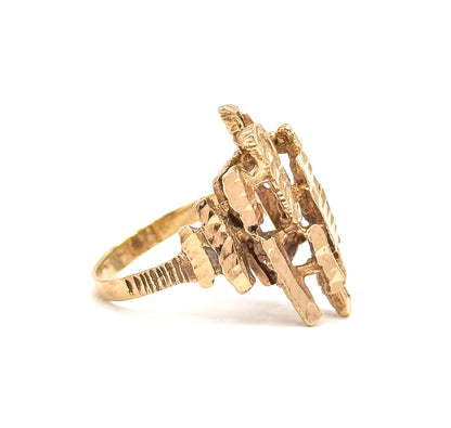 Side profile against white, showing how the slim textured shank rises and flares into the stacked, faceted gold bars that project outward from the finger.