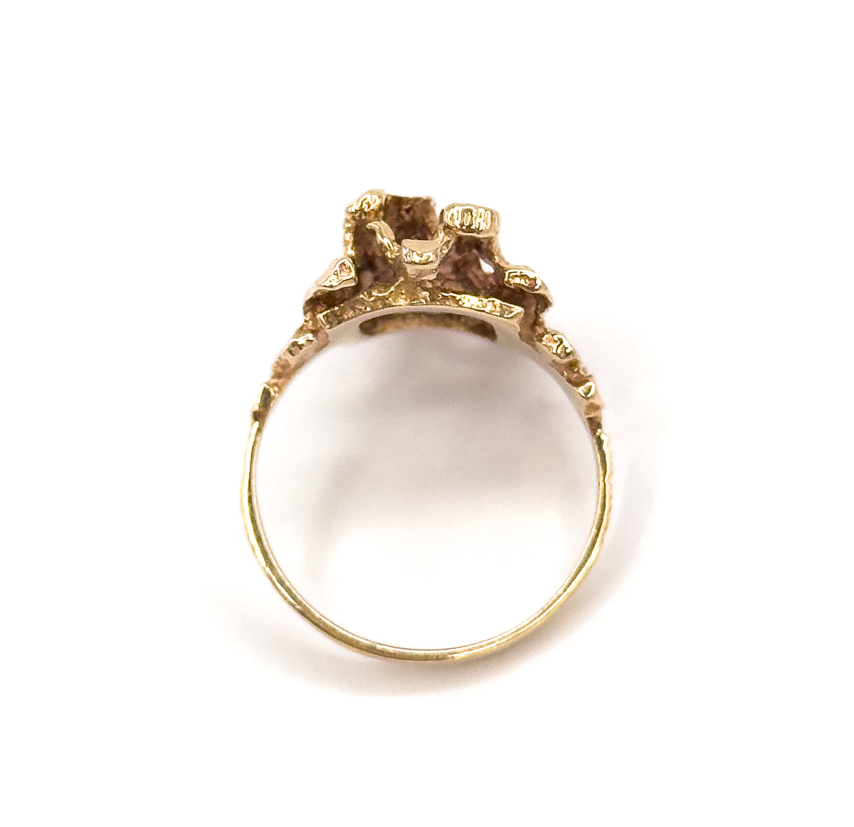 Viewed straight through the open circle of the slim shank, so the underside gallery of the faceted yellow gold head is seen from beneath, its bars meeting in an open framework.