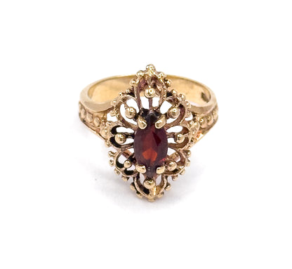 Looking straight down on the navette face, the marquise garnet sits upright at the centre within scrolled openwork and clustered beads, the shank tapering away to either side.