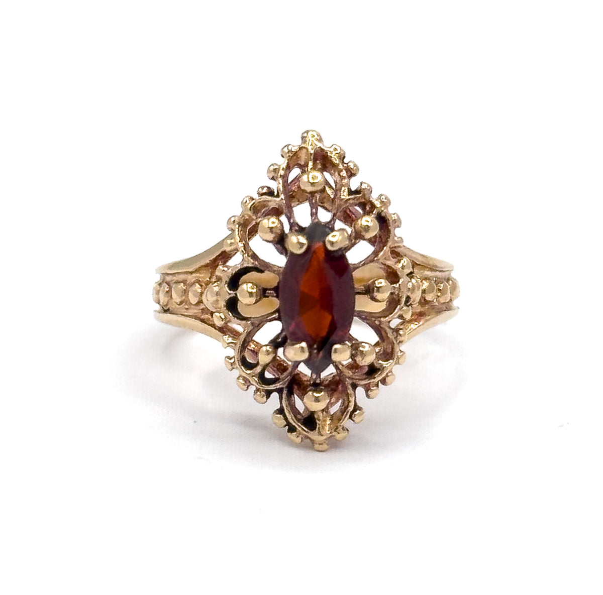 Face-on and close in, the marquise garnet stands proud in its scalloped bead-set bezel, with the split shoulders and their beaded rows visible on both sides of the navette face.
