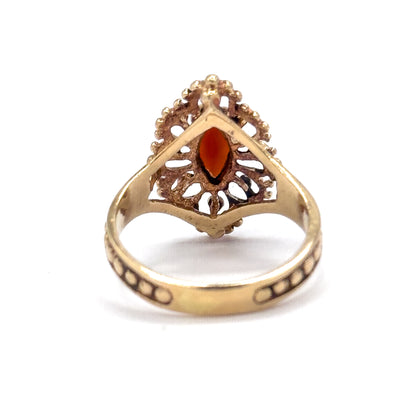 The underside of the navette face, open gallery pierced with scrolled cut-outs revealing the back of the marquise garnet, with the beaded shank sweeping below.