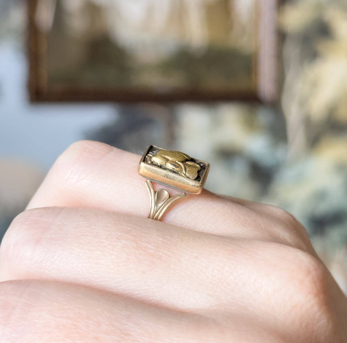 Close view from the side, shown on a finger, where the rectangular bezel sits high above a heart-shaped join that splits into the tapering shank.