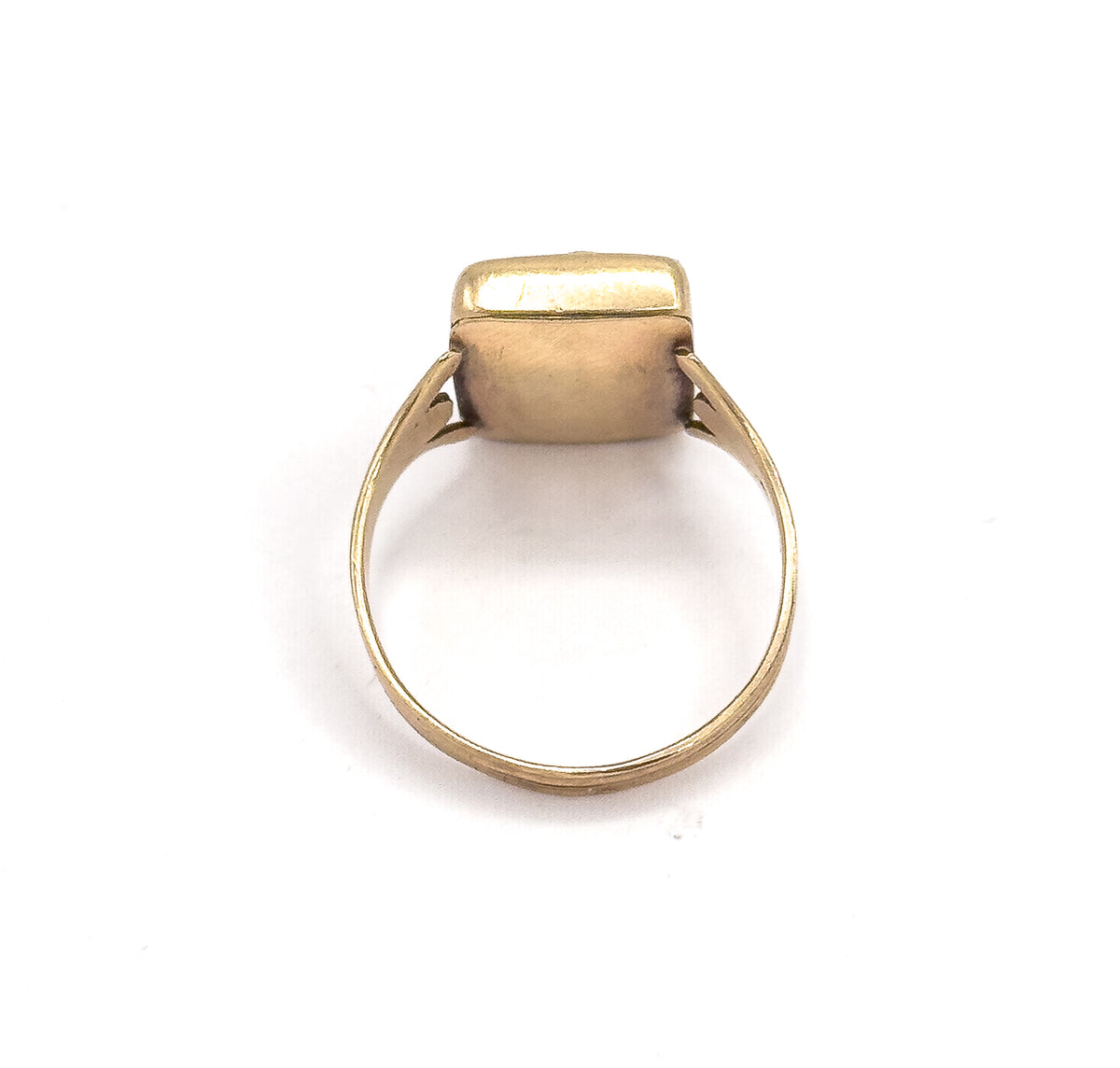 Viewed from behind the head on white, the smooth back of the bezel box and the pierced shoulders meet the full circle of the tapering shank.