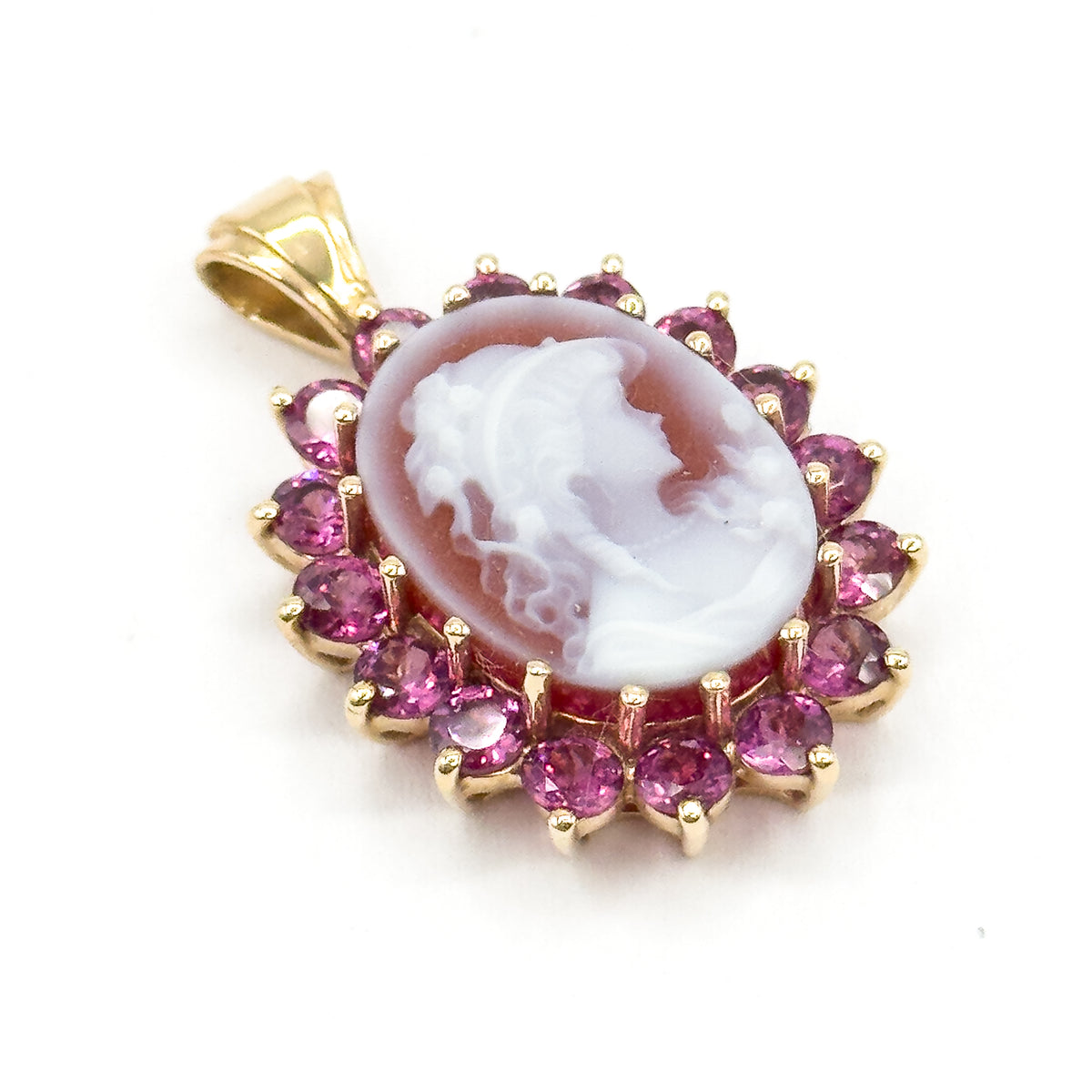 Closer three-quarter view with the bail upright at the upper left, bringing out the curls, drapery and layered carving of the pale figure against its darker ground inside the garnet halo.