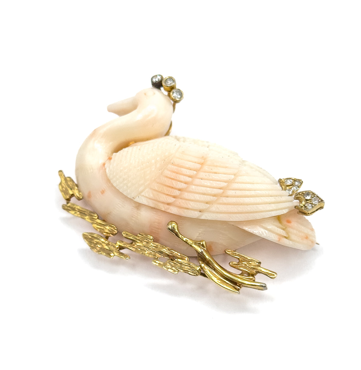 A three-quarter view from the tail end, the carved coral body receding toward the dipped head at upper left, diamond clusters at the crown and along the back, gold reeds trailing below.