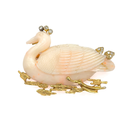 A full side profile against white, the coral swan facing left with three diamonds crowning its head, two more on the back, and textured gold reeds framing the base.
