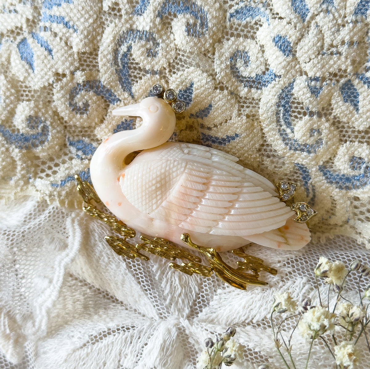 A closer, slightly turned view showing the swan's raised neck and beak, the small diamond cluster above its head, and the finely carved feather rows sweeping back over the body.