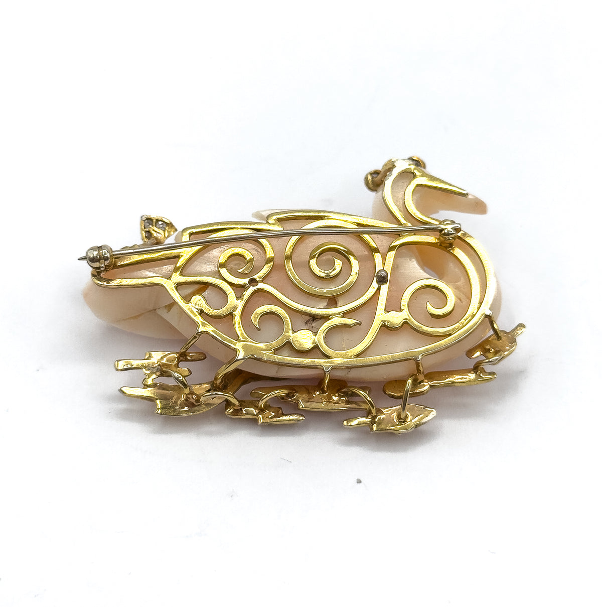 The full reverse against a plain white background, with the swirling openwork gallery, the pin stem crossing from hinge to catch, and the gold reeds splaying out below.