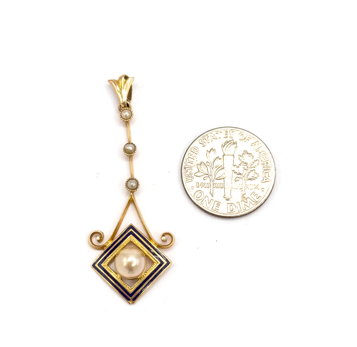 Shown upright beside a dime for scale, the pendant standing roughly as tall as two coins from fluted bail through the seed pearl bar to the cobalt enamel square.