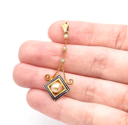 Shown resting across the fingers of an open hand, which gives its size — the bail sits by the fingertip and the cobalt blue enamel square with its creamy pearl reaches the lower knuckles.