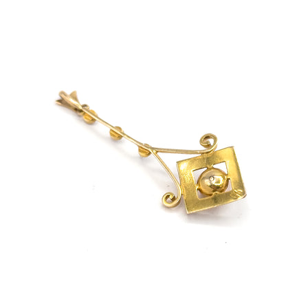 Angled view on plain white from the reverse side, the open square frame seen from behind with the creamy pearl seated through its centre and the three seed pearls along the slender bar.