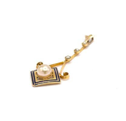 Tipped at a low angle so the enamel square faces the camera, its stepped cobalt borders and the milgrained bezel around the creamy pearl clear while the seed pearl bar recedes to the bail.