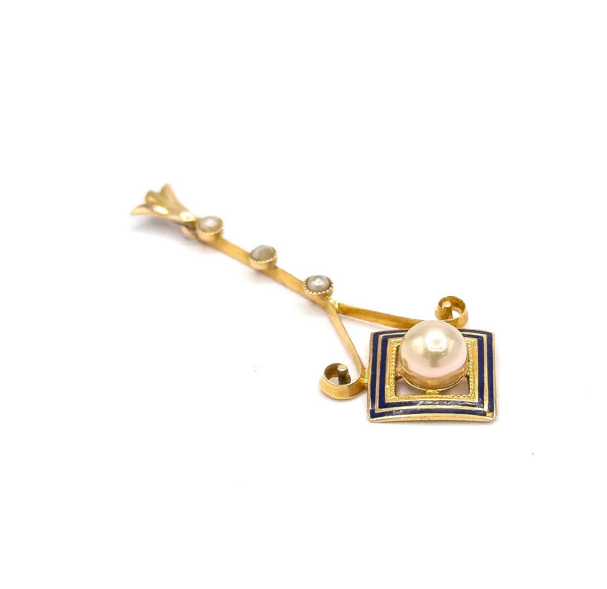 Diagonal view from above with the bail at the upper left, bringing out the two small gold scroll curls where the slender seed pearl bar joins the cobalt blue enamel square.