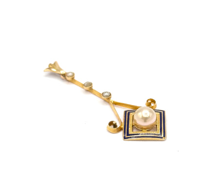 Diagonal view from above with the bail at the upper left, bringing out the two small gold scroll curls where the slender seed pearl bar joins the cobalt blue enamel square.
