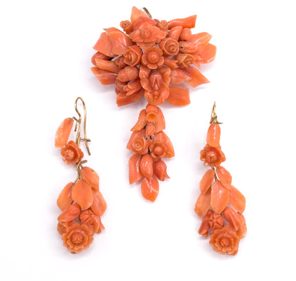 Almost the same view with slightly different angle, the pendant brooch upright at the top and the two carved coral earrings set further apart below, their gold hooks turned outward.
