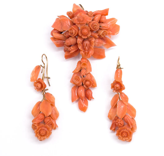 Almost the same view with slightly different angle, the pendant brooch upright at the top and the two carved coral earrings set further apart below, their gold hooks turned outward.