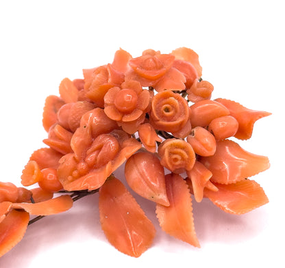 An extreme macro crop of the cluster, the spiralled centres of the coral roses and the saw-toothed edges of the carved leaves filling the frame with the gold stem wire glimpsed behind.
