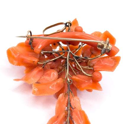 The reverse of the pendant brooch, showing the long yellow gold pin stem, catch and bail above a framework of gold branch wires holding the carved coral from behind.