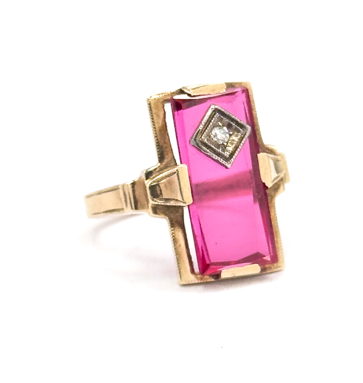 Off the hand now, angled three-quarter view against white, showing the yellow gold prongs gripping the long red stone and the shank tapering away behind the raised face.