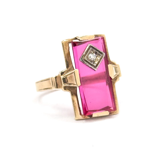 Off the hand now, angled three-quarter view against white, showing the yellow gold prongs gripping the long red stone and the shank tapering away behind the raised face.