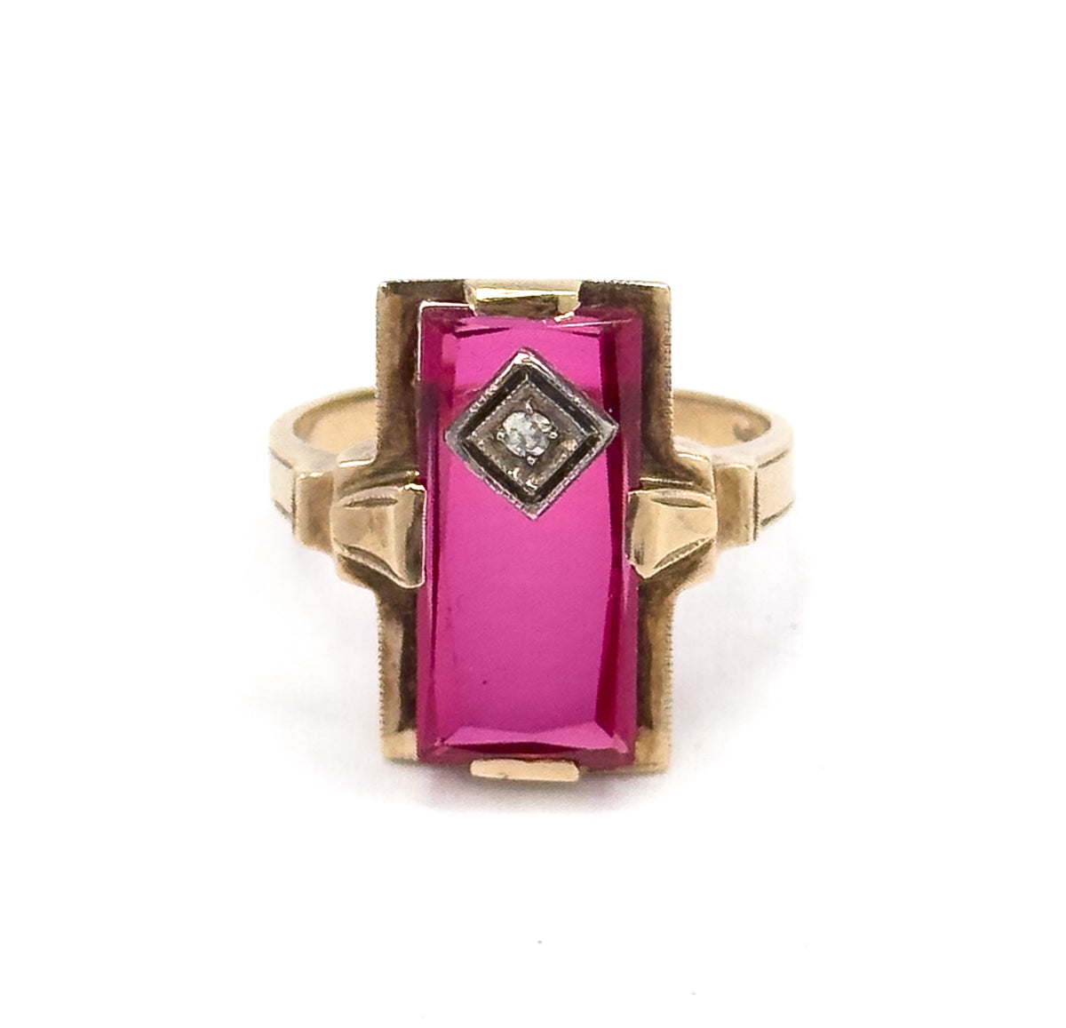 Straight-on front view with the ring upright, the long table-cut ruby filling the rectangular face between corner prongs, the diamond in its square bezel above, flared shoulders either side.
