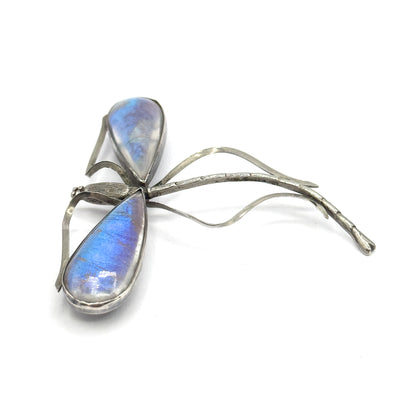Seen from above with both teardrop domed wings glowing blue and violet, the beaded head at the left, and the two bare wire wing frames sweeping right beside the long tapering tail.
